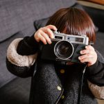 A child pretending to be photographed with a camera.