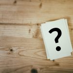 Question mark on wooden desk background. Concept for confusion, question or solution.