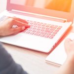 Close Up of woman hands using mobile phone and laptop computer business with blank copy space screen for your business advertising text message or content business in the morning light.
